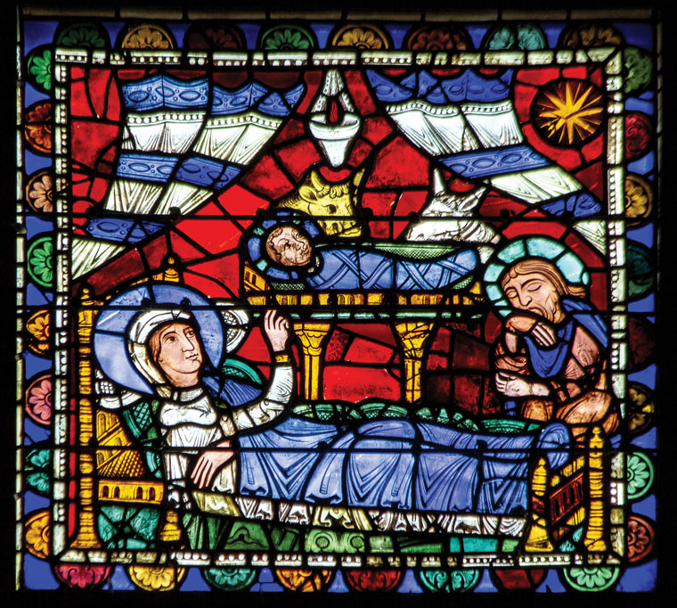 Vitrail représentant la Vierge Marie allongée sur un lit, désignant Jésus dans  la crèche, Joseph endormi au pied du lit