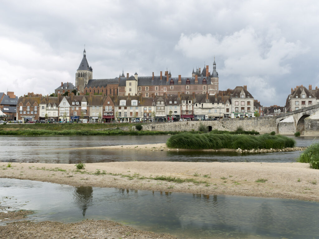 La Loire avec une rangée de maisons et le château de Gien en briques en arrière-plan